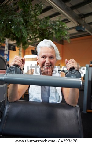 Happy senior woman doing weight training in gym
