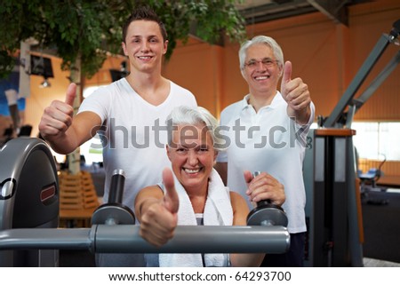 Successful fitness team in a gym holding thumbs up