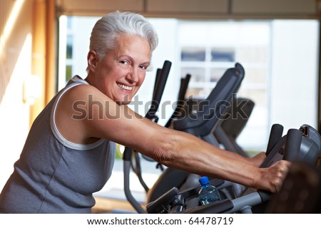 Happy senior woman exercising on bike in gym