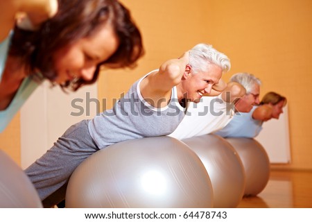 Group in gym doing back exercises on Swiss balls