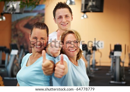 Three happy gym employees holding thumbs up