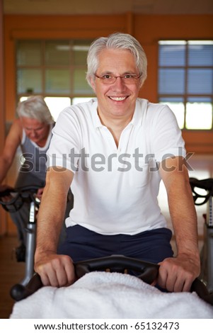 Elderly man on bike in a gym