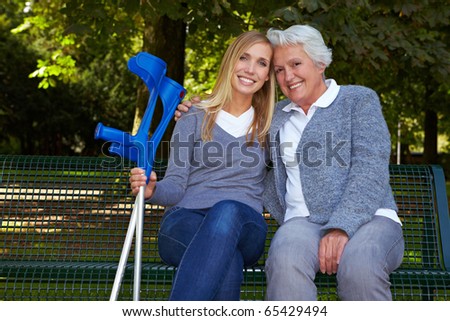 Smiling granddaughter with handicapped grandmother on park bench