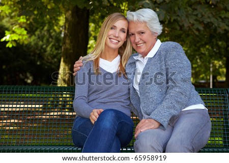 Young blonde woman sitting with her grandmother on a park bench