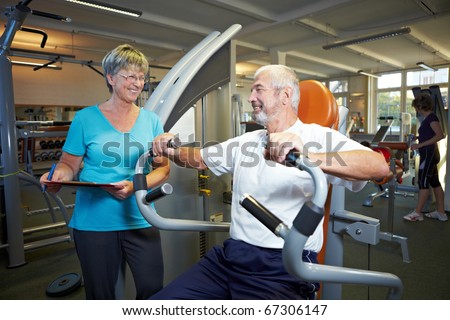 Fitness trainer explaining rowing machine in gym
