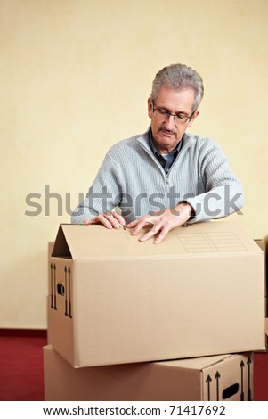 Elderly man opening the lid of a packing case while relocation house
