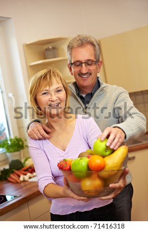 Elderly man taking apple from woman with fruit bowl