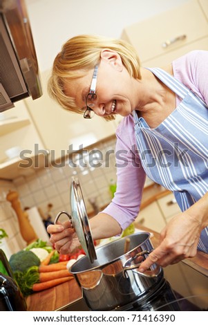 Elderly woman in kitchen on a stove cooking soup