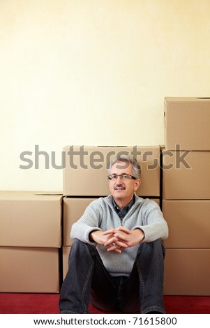 Senior man sitting relaxed in front of moving boxes