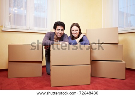 Happy smiling couple sitting behind many moxing boxes