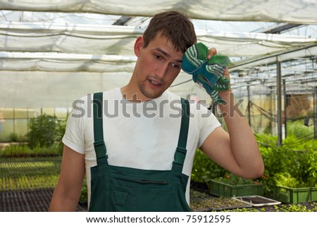 Tired farmer wiping off his sweat in a hot greenhouse