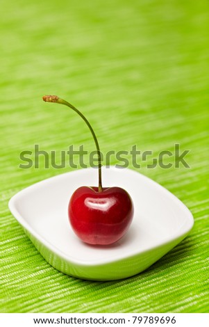 Single red cherry in a white bowl