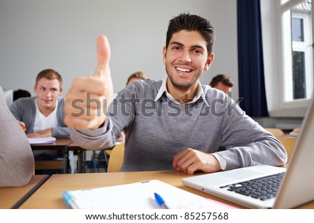 Happy student holding his thumb up in university class