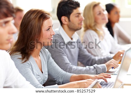 Happy female student with computer in university class