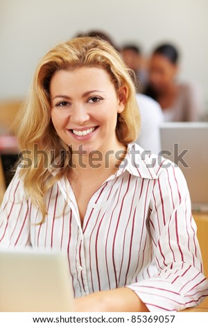 Smiling female student at laptop in university class