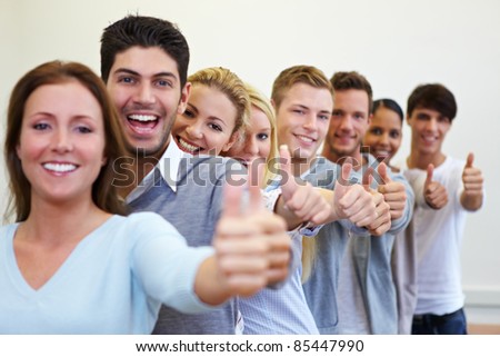 Happy smiling students in a row with their thumbs up