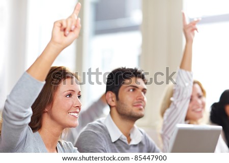 Two women raising hands in university class