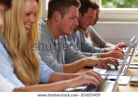 Happy students using their laptops in university class