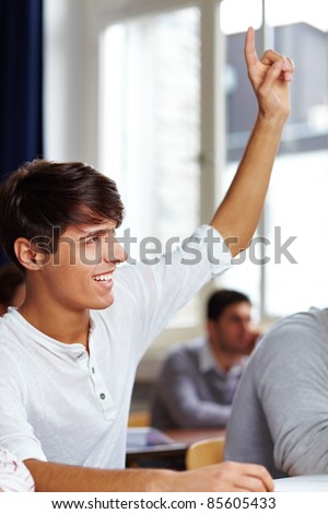 Happy student raising his finger in university class