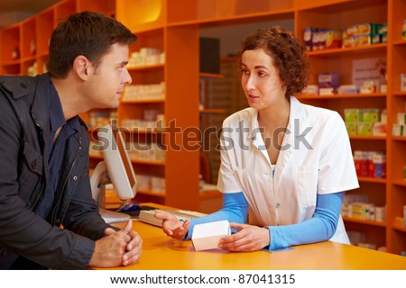 Happy pharmacist talking to customer in a pharmacy