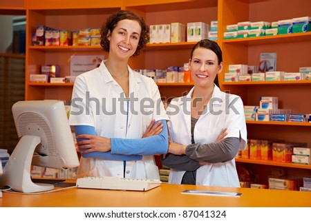 Two happy pharmacists with her arms crossed in pharmacy