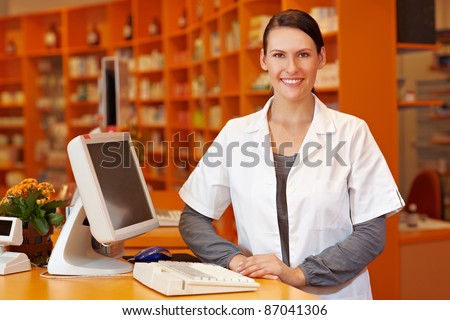 Happy pharmacist standing at checkout counter in a drugstore