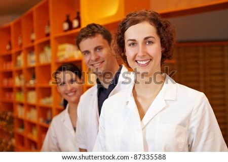 Three competent pharmacists smiling in a pharmacy