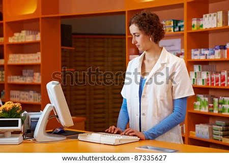 Pharmacist at checkout booth in pharmacy using a computer