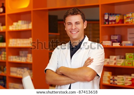 Happy pharmacist in pharmacy with his arms crossed
