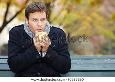Shivering man in autumn drinks a cup of tea
