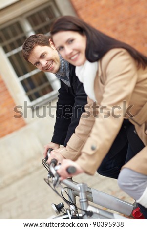 Happy couple cycling with bikes in the city