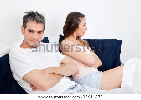 Couple with problems remaing silent with arms crossed in bed