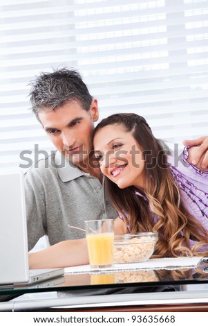 Elderly couple looking at laptop at breakfast table