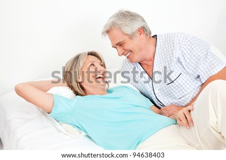 Senior couple laying laughing in bed in the bedroom