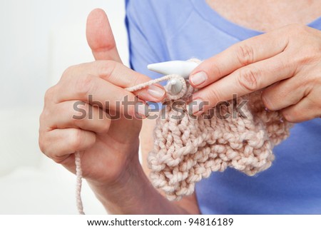Hands of senior woman knitting with wool and knitting needles