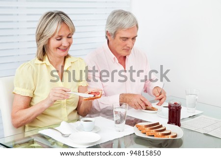 Married senior couple eating breakfast together with toast and jam