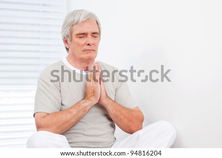 Senior man at relaxing meditation exercise in gym