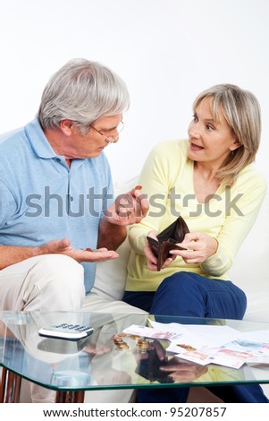 Elderly couple with empty wallet discussing financial issues at home