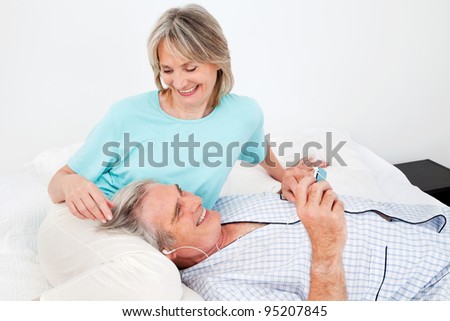 Happy senior man listening to music with headphones and small player