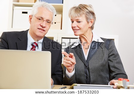 Business woman helping colleague with his laptop computer in the office
