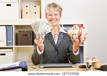 Smiling happy elderly business woman with dollar bills and a piggy bank