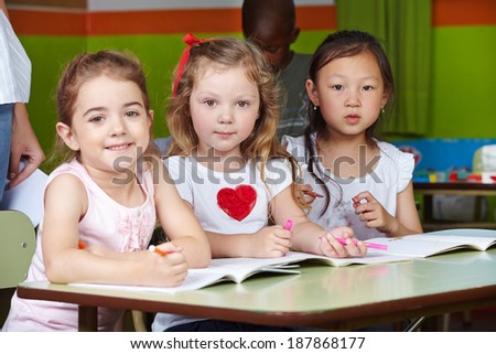 Children in kindergarten with pens and coloring book at a table