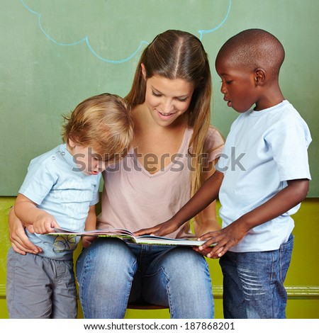 Children and kindergarten teacher reading together in a book
