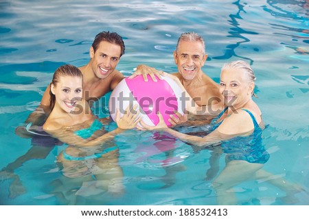 Happy group playing in swimming pool with a water ball in summer