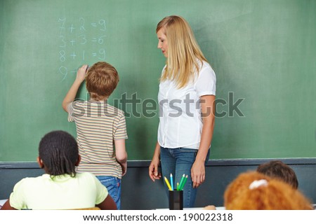 Child doing math in chalkboard in elementary school class