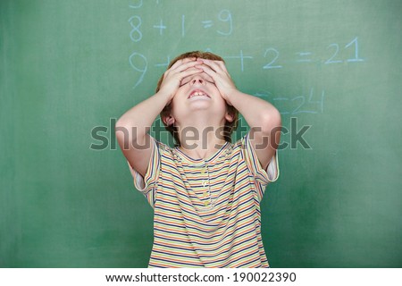 Child with dyscalculia in front of chalkboard in elementary school