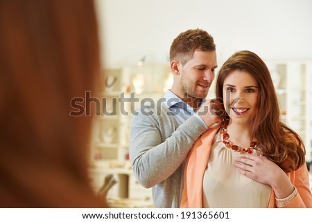 Man helping woman with fitting of a necklace at jeweler store