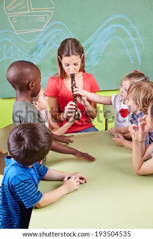 Nursery teacher playing flute for children in a kindergarten