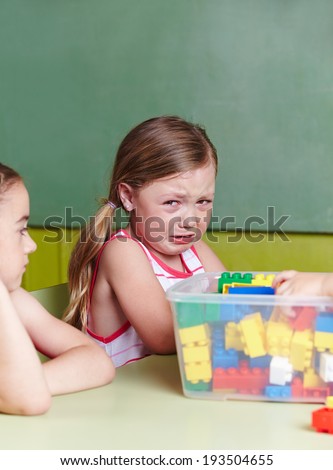 Sad girl crying in a kindergarten group