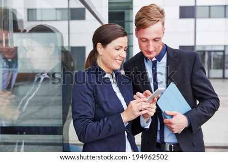 Two business people looking together at smartphone in the city